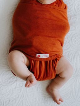 Embe swaddle Rust. Den intelligenta Embé-dragkedjan och lindningsdesignen hjälper till att använda lindningen på rätt sätt. Det förhindrar överspänning av bäckenområdet, vilket kan orsaka höftledsdysplasi under en längre tid.
